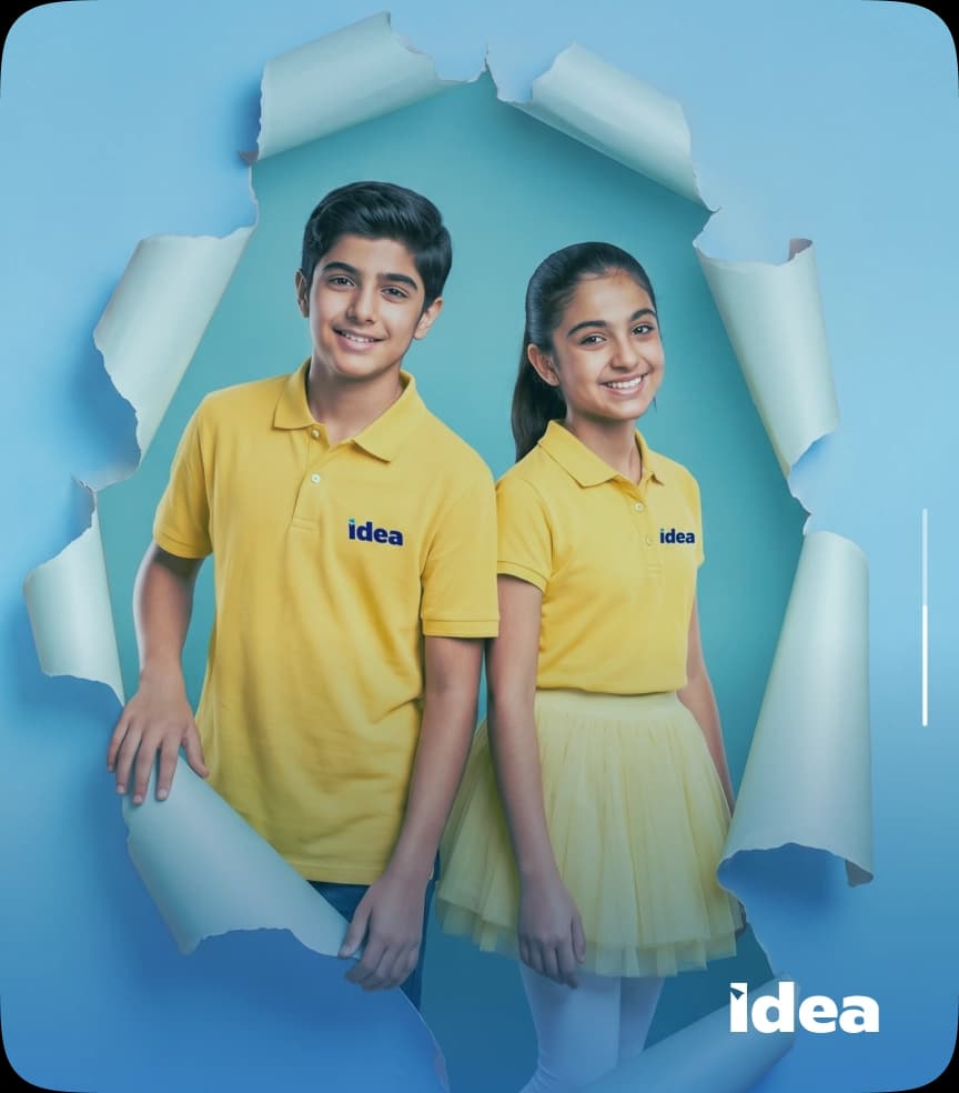 Two IDEA students in uniform stepping through a torn paper backdrop